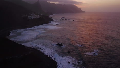 Aufschlussreiche-Luftaufnahme-Der-Vulkanischen-Klippen-Von-Teneriffa-Mit-Plätschernden-Wellen-Während-Des-Sonnenuntergangs