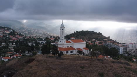 Luftdrohnenaufnahmen-Einer-Kirche-Auf-Einem-Hügel-Mit-Licht-Im-Hintergrund-In-Der-Nähe-Von-Madeira