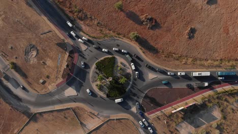 Top-down-drone-view-of-a-busy-roundabout-in-Portugal,orange-and-green-earthy-tones
