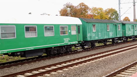 Panoramic-view-of-a-composition-of-green-passenger-sleeping-wagons-on-a-railway-platform-in-a-small-town