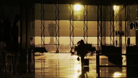 Silhouette-Eines-Mädchens,-Das-Mit-Koffer-Im-Flughafen-Läuft,-Goldenes-Sonnenlicht