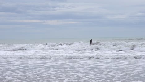 Slow-motion-of-a-surfer-on-a-stormy-day-in-the-Mediterranean-Sea,-ride-the-wave-with-dirty-water-and-gray-day