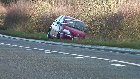 A-small-red-car-covered-with-police-aware-tape-after-crashing-into-a-hedge-near-to-Melton-Mowbray-in-Leicestershire,-England,-UK