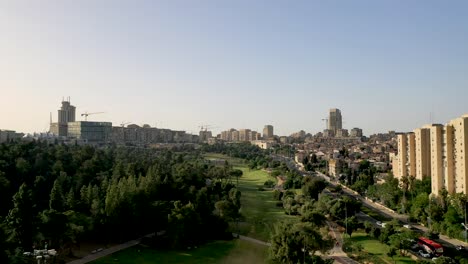 Aerial-forward-fly-over-Sachet-park-in-Jerusalem,-tall-buildings-on-the-right-hand-side,-forward-drone-fly-shot
