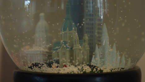 A-close-up-of-a-model-of-Saint-Paul's-Cathedral,-Minnesota-in-a-snow-globe-with-flakes-falling