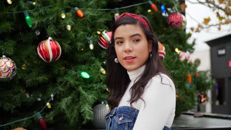 Eine-Wunderschöne-Hispanische-Frau-Draußen-In-Der-Stadt,-Die-Mit-Einem-Weihnachtsbaum-Ihre-Weihnachtsgeschenke-Einkauft