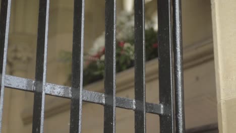 Metal-bars-across-church-entrance-with-flower-display