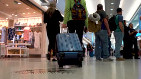 Die-Beine-Und-Das-Gepäck-Einer-Frau,-Die-Durch-Einen-Geschäftigen-Flughafen-Geht