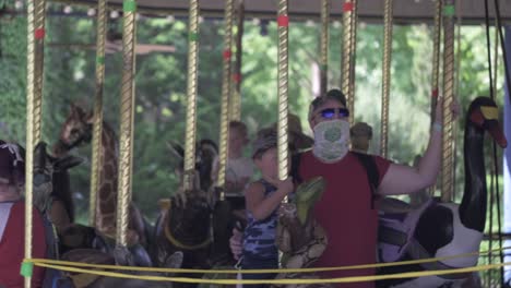People-with-virus-masks-on-carousel.-Slomo,-static