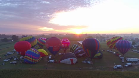 Luftaufnahme-Eines-Morgendlichen-Starts-Von-Heißluftballons-Bei-Einem-Ballonfestival-Vom-Befüllen-Bis-Zum-Abheben,-Wie-Von-Einer-Drohne-Gesehen