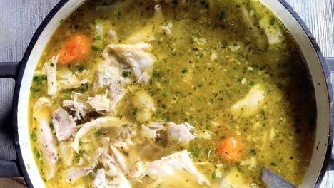 overhead-closeup-ladle-stirring-of-homemade-chicken-noodle-soup-with-carrots-in-large-pot