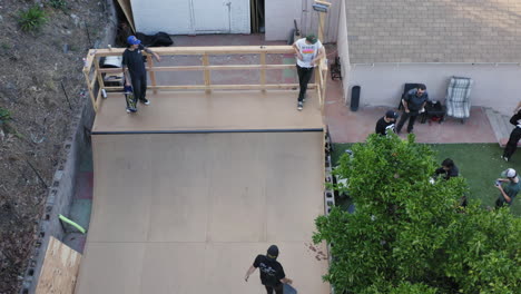 People-skating-on-backyard-ramp,-aerial-view