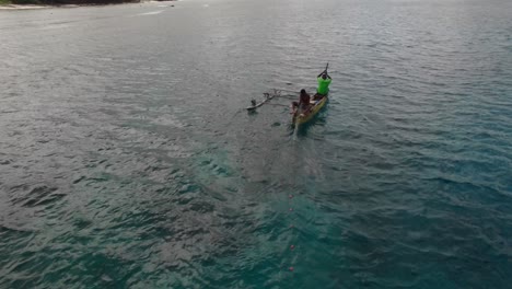 Local-Fishermen-Speading-Fishing-Net-by-Coast-of-Vanuatu-Island-From-Boat-With-Outrigger,-Aerial-View