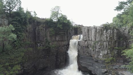 Aufsteigende-Luftaufnahme-Eines-Wasserfalls-Mit-Hoher-Kraft-In-Der-Grafschaft-Durham-An-Einem-Dunklen-Und-Launischen-Tag