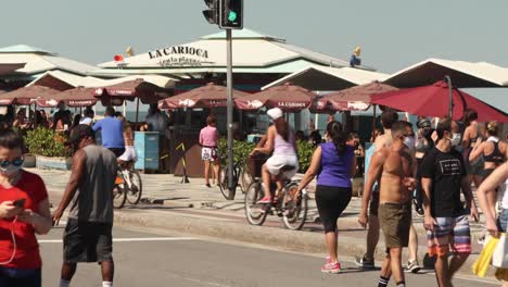 Outdoors-sports-and-recreational-activity-on-Ipanema-boulevard-with-people-walking,-biking-and-running-along-the-palm-trees-flagged-beach-that-is-off-limits-during-the-COVID-19-coronavirus-outbreak