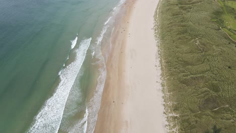 Meereswellen,-Die-An-Einem-Sommertag-Zum-Weißen-Sandstrand-Des-Whiterocks-Beach-In-Portrush,-Nordirland,-Laufen---Luftaufnahme
