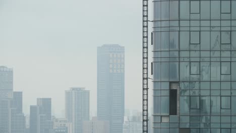 High-rise-buildings-made-of-steel-and-glass-with-air-pollution-haze-from-coal-ash-in-the-distance,-handheld-shot
