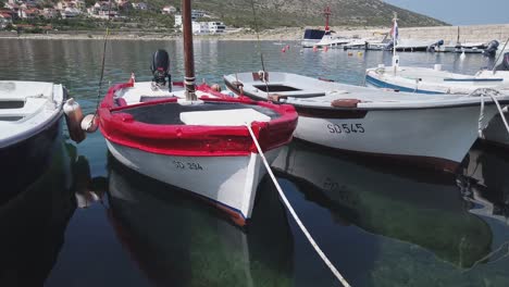 Small-colorful-fishing-boats-bob-gently,-moored-in-a-Croatian-marina