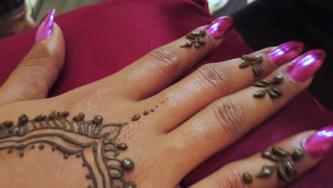 close-up-shot-of-an-elegant-and-manicured-womans-hand-with-pink-nails-receiving-a-traditional-henna-tattoo-in-little-india-in-Singapore