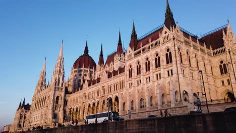 Ungarns-Parlamentsgebäude-An-Der-Donau-Während-Der-Goldenen-Stunde-Mit-Menschen-Und-Verkehr