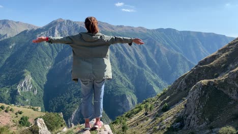 Girl-standing-on-the-edge-of-the-cliff-high-in-mountains