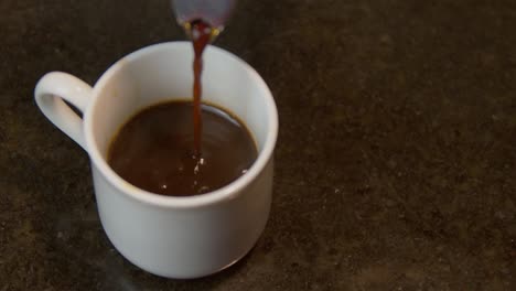 Gießen-Sie-Heißen-Kaffee-Auf-Die-Weiße-Tasse-Aus-Der-Moka-Kanne-–-Nahaufnahme