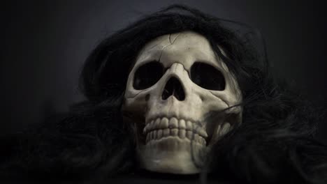 Creepy-skull-with-black-hair-on-dark-background-medium-zoom-in-shot