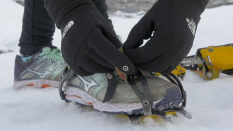 Close-Up-of-Gloved-Hands-Strapping-on-Crampons,-Gearing-up-for-a-Glacier-Hike,-Slow-Motion
