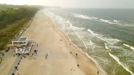 Beach-Pullback-Aerial-Drone-Over-Cold-Families-Enjoying-Gloomy-Evening-at-Wladyslawowo-Beach,-Poland