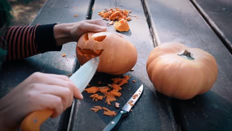 Woman-carving-pumpkins-for-Halloween-on-wooden-table