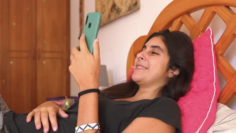 girl-Laughing-Doing-Video-Chat-Using-Mobile-Phone-In-Bed
