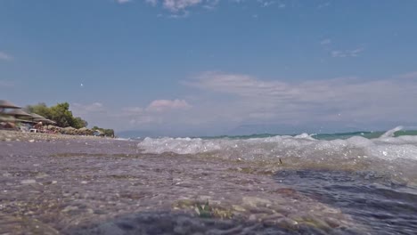 Low-ground-view-of-waves-hitting-the-seashore-at-Chrani-beach,-Messinia,-Peloponnese-,-Greece-60fps