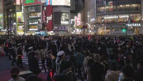 Línea-De-Policías-Parados-En-Un-Carril-Peatonal-Manteniendo-El-Orden-En-El-Cruce-De-Shibuya-En-La-Noche-De-Halloween-En-Tokio,-Japón---Cámara-Lenta-De-Tiro-Medio