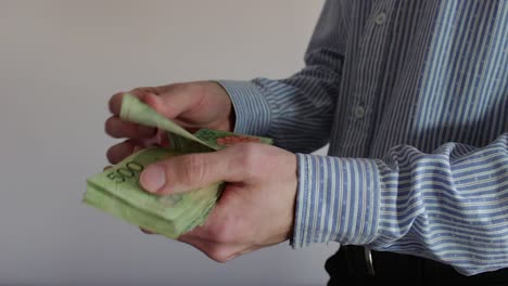 Young-businessman-counting-Argentine-cash-money-"pesos".-Close-up
