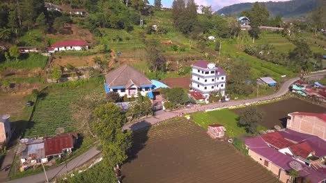 Luftaufnahme-Eines-Dorfes-In-Indonesien,-Umgeben-Von-Gemüsefarmen,-Bäumen,-Feldern,-Vulkanen-Und-Bergen-An-Einem-Sonnigen-Tag