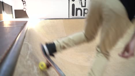 Professional-skater-riding-in-skateboard-hall,-grinding-on-rail-ramp-during-sunny-day-indoor-during-covid19-pandemic