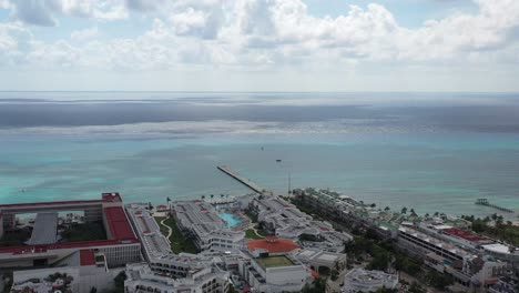 Aerial-shot-heading-the-sea-shows-big-hotel-by-the-Caribbean-and-a-pier