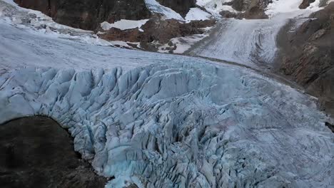 Slow-shot-tilting-up,-revealing-more-of-the-glacier-next-to-the-rocky-cliff