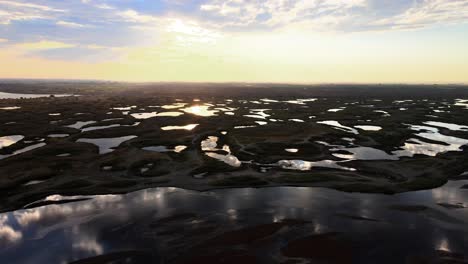 Aerial-panorama-of-scattered-lakes-reflecting-a-golden-sunrise,-Potholes,-Washington