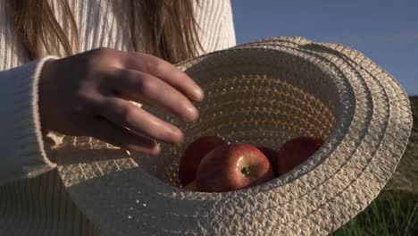 Mujer-Mostrando-Manzanas-Rojas-En-Un-Sombrero-De-Paja-Plano-Medio