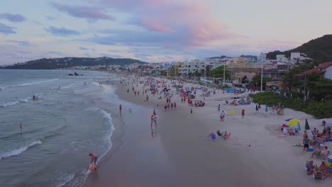 Aerial-dolly-in-flying-over-Bombas-beach-and-pink-sunset-light-reflecting-on-the-sand