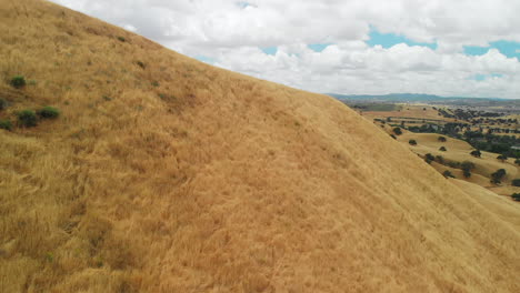 Reveal-of-Dry-Grass-Hill-Landscape-from-Behind-Hill,-Aerial