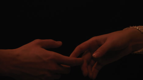 Männliche-Und-Weibliche-Finger-Berühren-Sich-Langsam-Vor-Schwarzem-Hintergrund,-Nahaufnahme