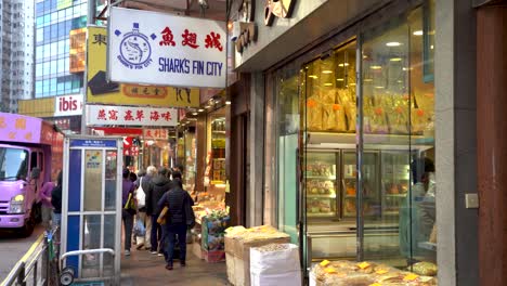 Hong-Kong,-Des-Voeux-Road-West-Sheung-Wan,-Dried-Seafood-Street-Including-Sharks-Fin-in-Illegal-Wildlife-Trade,-People-Passing-by-Shops