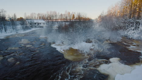 Statische-Ansicht-Des-Flusses-Durch-Verschneite-Landschaft-Und-Entferntes-Haus-In-Finnland