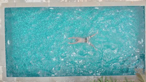 overhead-shot-of-young-fit-man-loose-casual-swimming-trunks-breast-stroke-small-private-home-pool