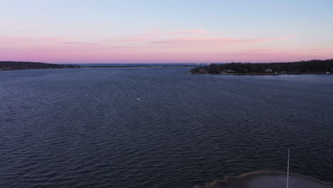 an-aerial-shot-over-a-bay-focused-on-an-island-during-a-beautiful-sunrise