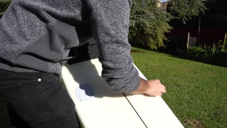 Putting-wax-on-the-surfboard-in-the-backyard