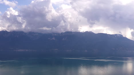 Aerial-hyper-lapse-of-clouds-rolling-over-mountains-near-lake