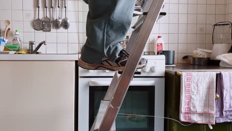 Home-Improvements---stepping-on-a-ladder-with-a-paint-bucket-in-one-hand